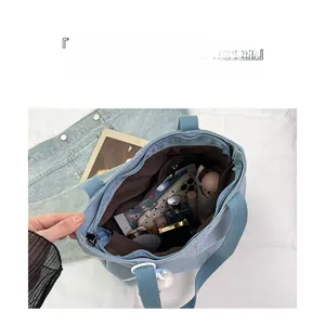 Detail view showing large interior capacity of a light blue canvas tote bag with personal items