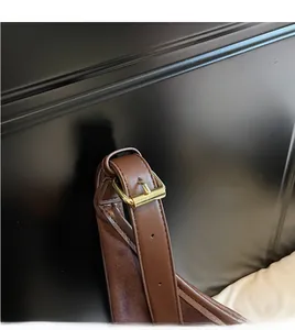 Détail de la bandoulière réglable en cuir marron foncé avec boucle en métal doré