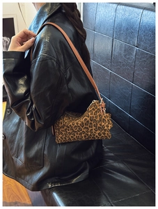 Detail of leopard print shoulder bag with leather strap and star charm on a model