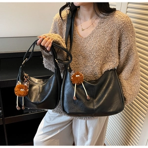 Close-up of small and large black PU leather hobo bags with leopard plush charms