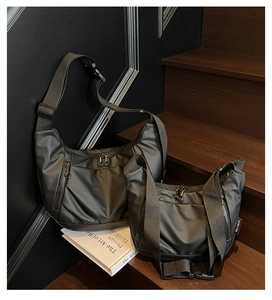 Size comparison of black Oxford cloth crossbody bags on a wooden step display