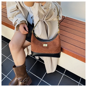 Detail of quilted brown suede shoulder bag with chain strap on a model outdoors