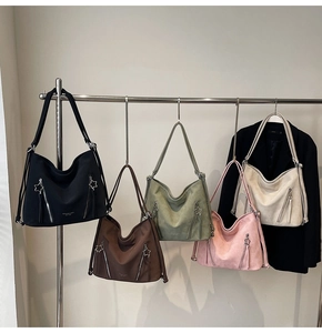 Selection of large tote bags in black, brown, green, and pink hanging on a display rack