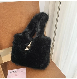Detail einer schwarzen Kunstfelltasche mit weißem Webknoten auf einer Holzfläche