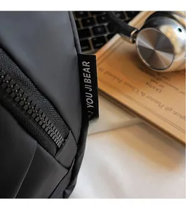 Detailed close-up of matte waterproof oxford fabric and brand label on a black crossbody bag