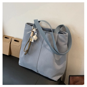 Detail of grey-blue canvas tote bag featuring thick texture and white pompom charm