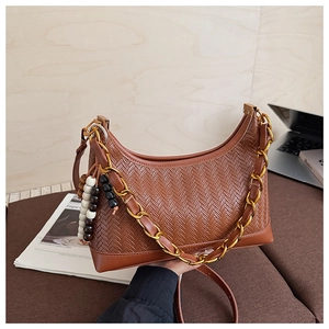 Detail of brown woven textured crescent bag with gold chain and wooden bead charm