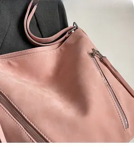 Close-up of pink frosted leather tote bag with MIKAXIQI branding on grey fabric