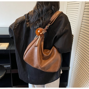 Brown leather hobo bag with wide shoulder strap and cute orange plush doll charm