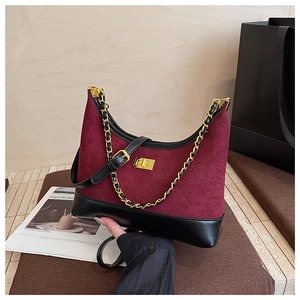 Detail view of burgundy quilted crossbody bag with gold chain and suede material texture