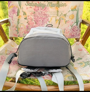 Gros plan du sac à dos outdoor gris avec détails en filet et boucle sur une chaise