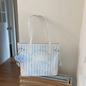 Détail du sac cabas à rayures bleues avec imprimé coquillage et pendentif en peluche