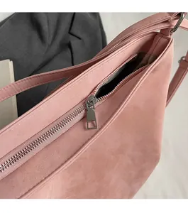 Detail of silver metal zipper on pink suede tote bag with brown patterned lining