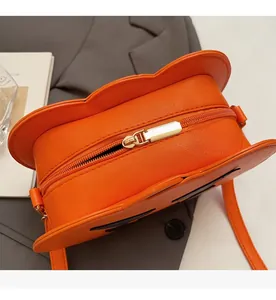 Close-up of the smooth golden zipper and cross-grain leather on the pumpkin bag