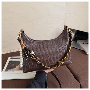 Detail of dark brown suede crescent bag with herringbone texture and gold chain link