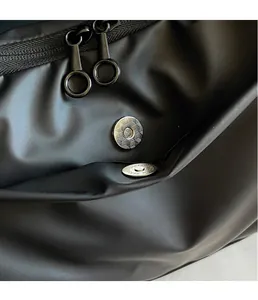Macro detail of high-quality magnetic snap and durable dual metal zippers on black oxford bag