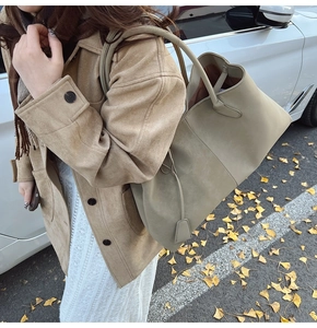 Detail of large olive green matte tote bag with shoulder strap in an autumn city setting