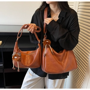 Detail view of large and small caramel brown leather shoulder bags with plush charm