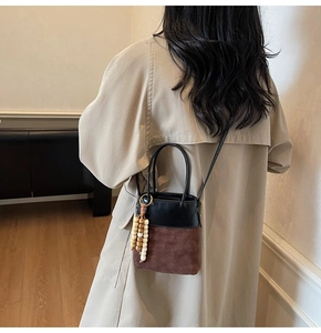 Detail view of the vintage bucket bag with faux suede stitching and decorative wooden beads