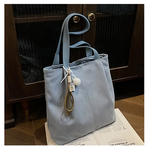 Close-up of light blue canvas tote bag with textured fabric and stylish pompom charm