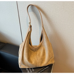 Detailed close-up of brown suede hobo bag with adjustable strap and brass buckle