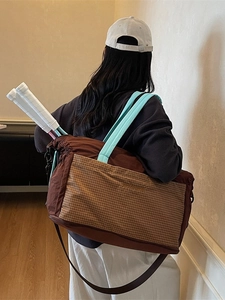 Brown nylon tote bag with blue handles holding two white tennis rackets in a lifestyle setting