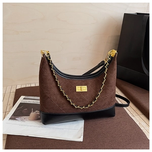 Close-up of quilted dark brown suede bag with gold buckle and metal chain strap detail