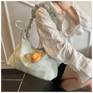 Detail of mint green pleated shoulder bag with ruffle strap and plush charm on model