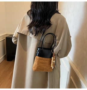 Detailed back view of vintage bucket bag featuring quilted suede and wood bead accent