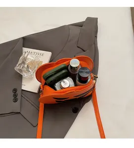Interior view of orange pumpkin bag showing spacious storage for phones and cosmetics