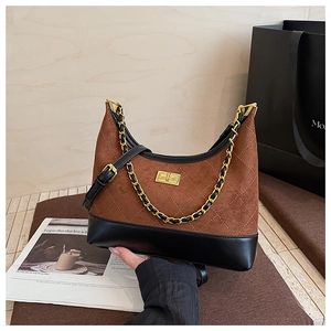 Close-up of quilted suede dumpling bag with gold twist lock and chain strap detail