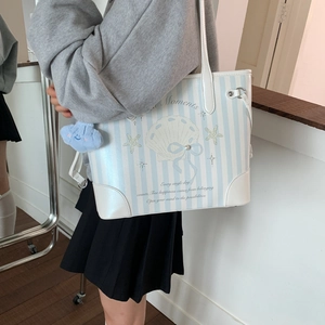 Détail du sac cabas rayé avec imprimé coquillage, breloque nuage et poignées blanches