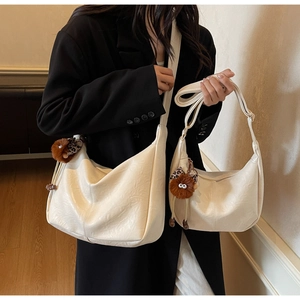 Detail of large and small beige hobo bags with leopard bow plush monster charms