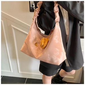 Detail of light pink pleated shoulder bag with moon embroidery and yellow plush charm