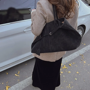 Detail view of large black matte suede tote bag with side metal ring and strap accents