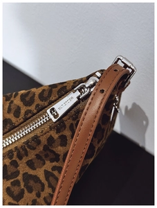 Close-up of leopard print bag texture with brown leather strap and silver zipper detail