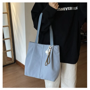 Detail of light blue canvas tote bag with a white pompom charm for casual daily use