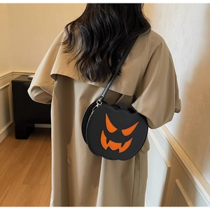 Detail of black leather pumpkin shoulder bag with orange Jack-o'-lantern face embroidery