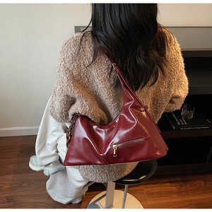 Détail du sac sous le bras bordeaux avec chaîne acrylique et texture en cuir synthétique