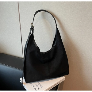 Detail of black suede hobo bag featuring gold metal buckle and adjustable leather strap