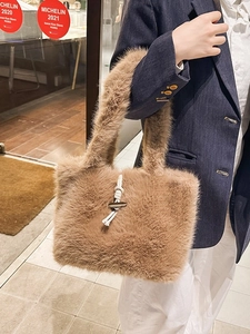 Braune Plüsch-Tragetasche mit Holzschnalle, getragen von einem Modell im Streetstyle