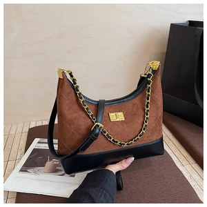 Detail of quilted suede dumpling bag with gold twist lock and chain strap