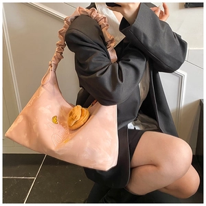 Close-up of pink ruched hobo bag featuring Love more embroidery and croissant charm