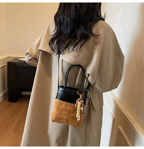 Detail view of mini bucket bag showing mixed leather textures and decorative wood beads
