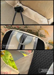 Détail du sac à dos kaki montrant la poche en filet à cordon et les coutures de la sangle
