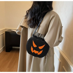 Detail shot of a black pumpkin crossbody bag with orange smiling face pattern on trench coat