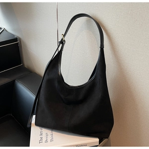 Detail of black suede tote bag with leather strap and golden buckle on minimalist background