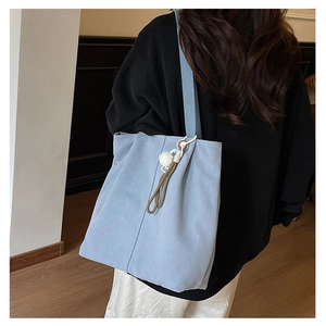 Detail view of light blue canvas tote bag featuring decorative brown rope and soft pom-pom
