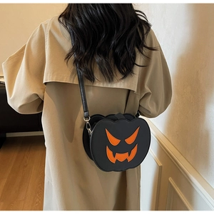 Detail of creative pumpkin crossbody bag with orange face on black leather surface