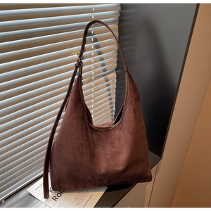 Detail of dark brown faux suede hobo bag featuring adjustable leather strap and metal buckle